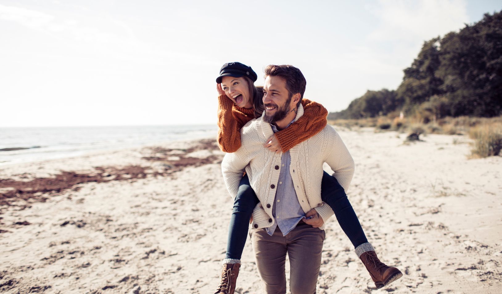 Man giving a woman a piggyback ride on the beach.